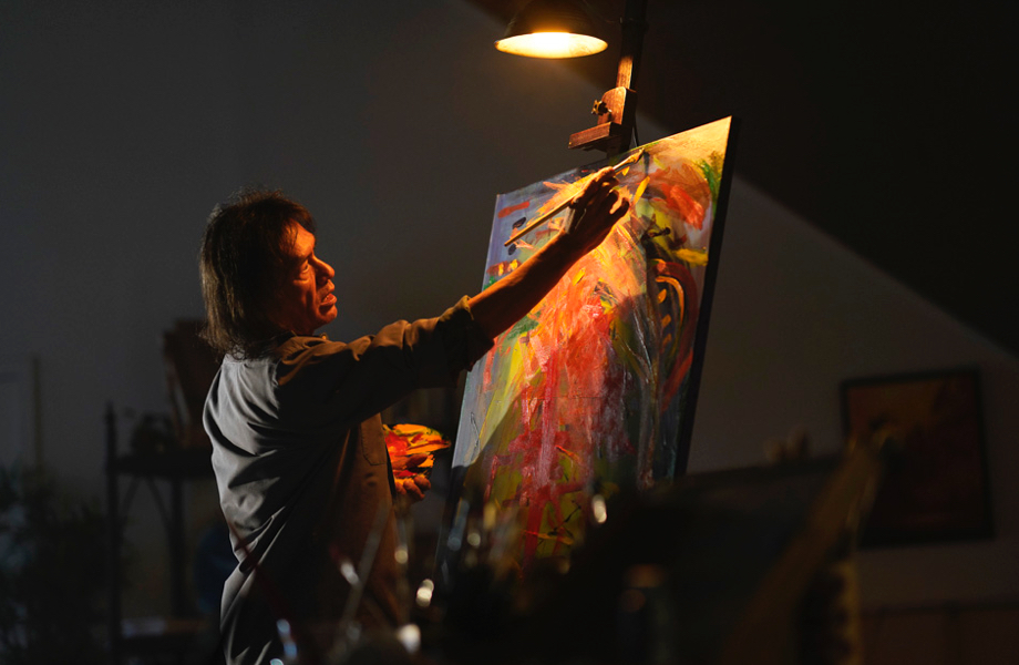 photo of a First Nations artist painting in his studio