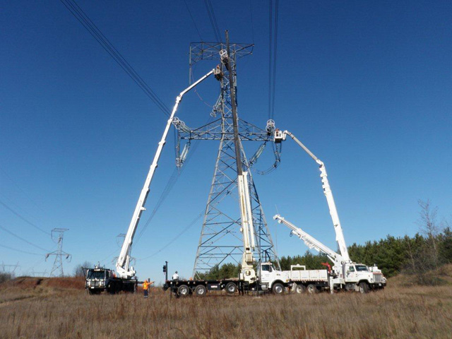 photo example of Hydro One vehicles working around a transmission tower which demonstrates why a 15-metre clear working radius is required