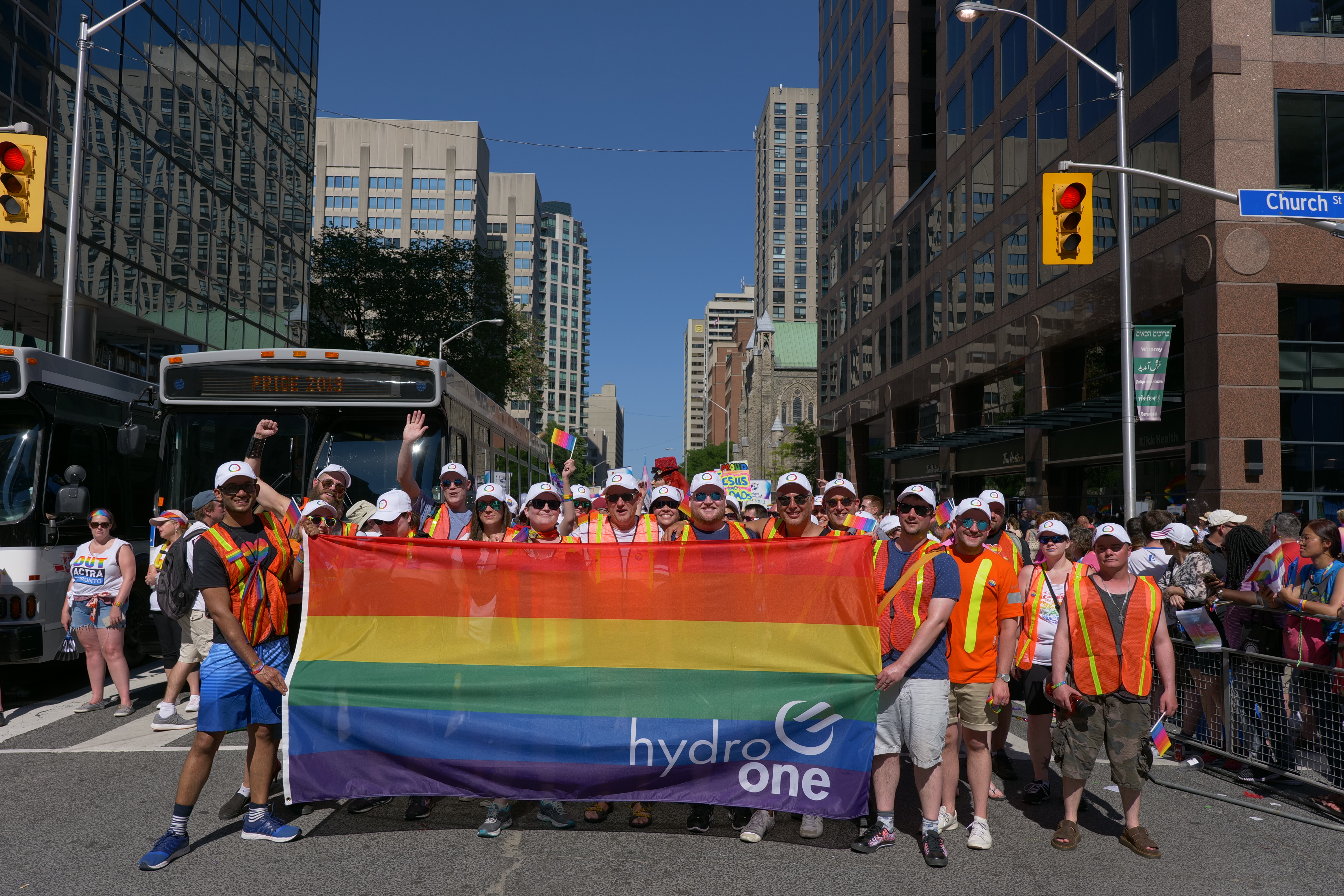 Photo of a group of Hydro One employees holding a large rainbow flag at a Pride event in Toronto