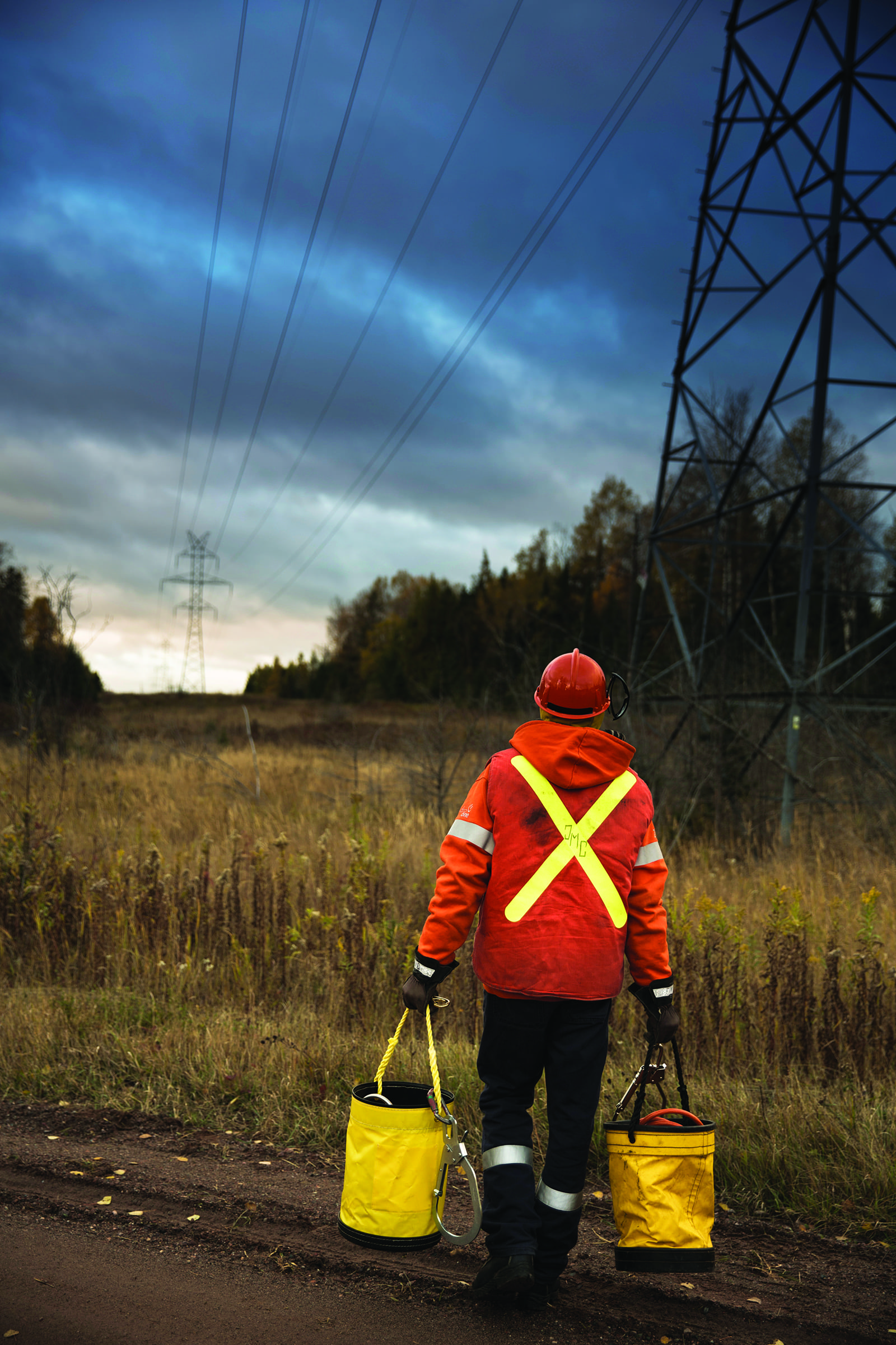 photo of a Hydro One worker carrying buckets on a Right of Way