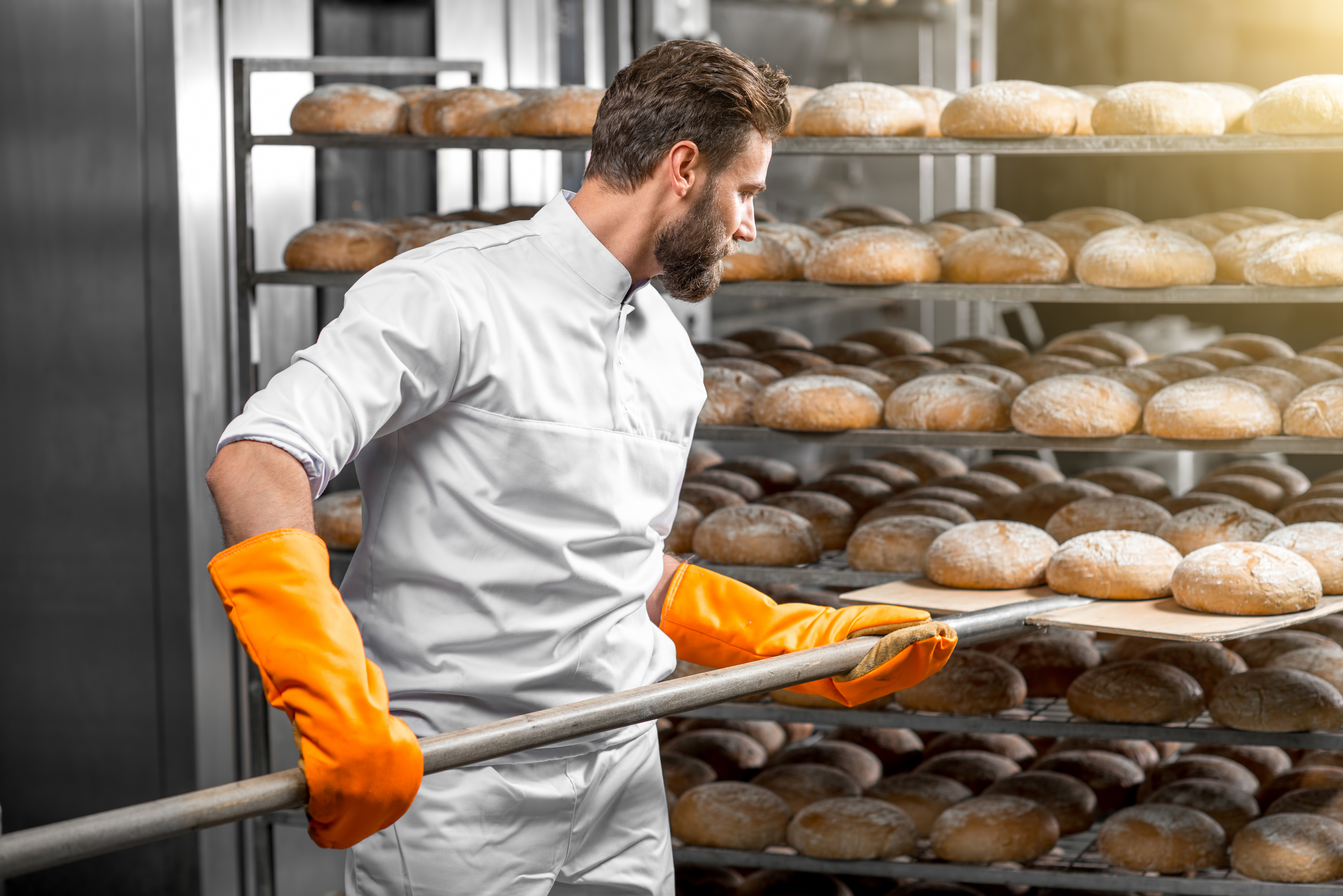 photo of a baker making bread in a large oven