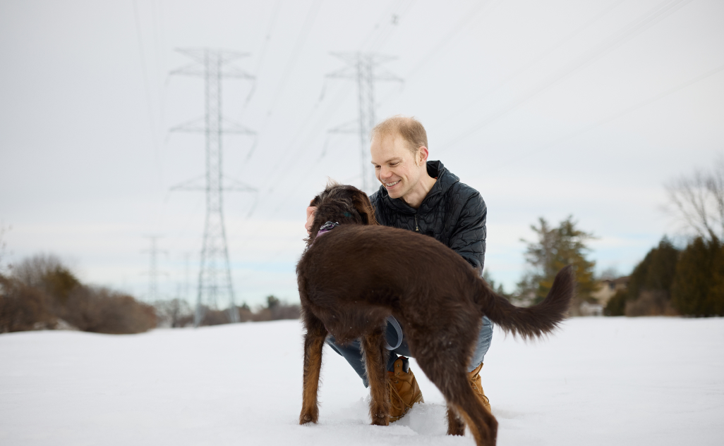Person petting dog infront of a transmission tower