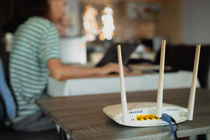 photo of a person using a computer with their broadband router in the foreground