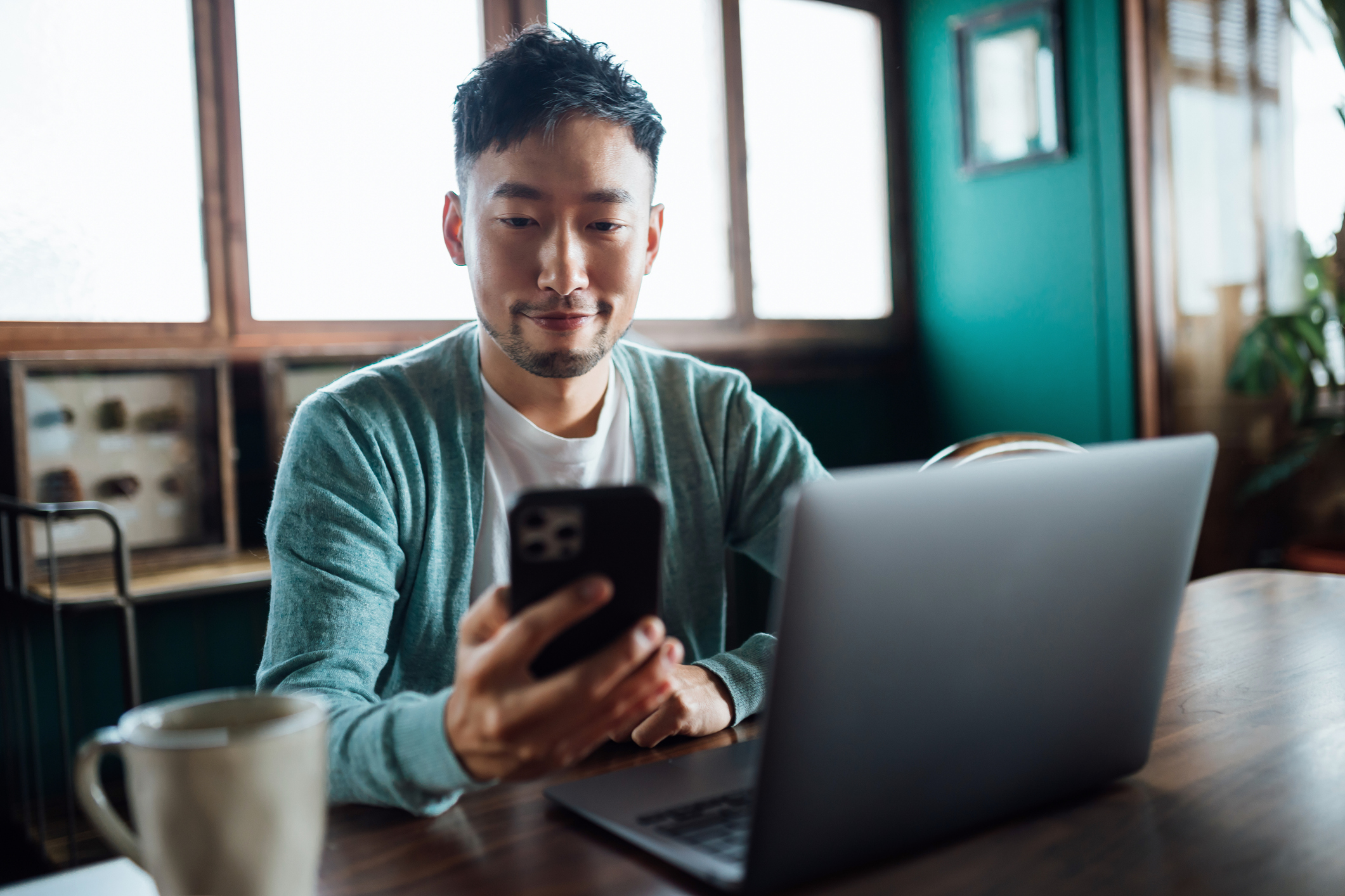 photo of a man using a laptop computer and mobile device