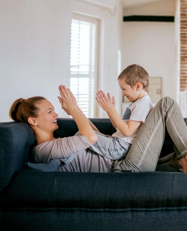 photo of a mother playing with her son on a couch