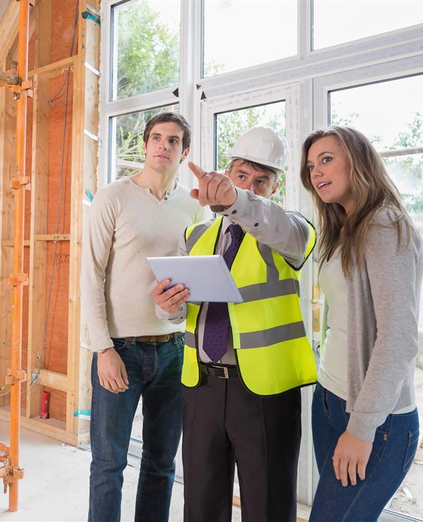 photo of a young couple with a contractor inside their new home