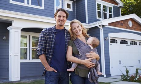 Image of a family of three standing infront of their home