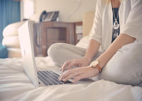 Woman sitting on a bed working on her laptop