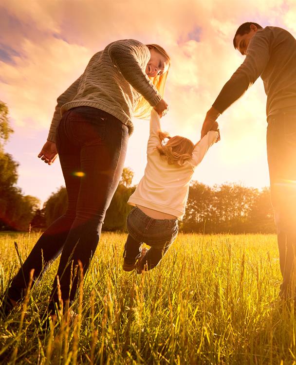 photo of a family playing wiht their child in a field