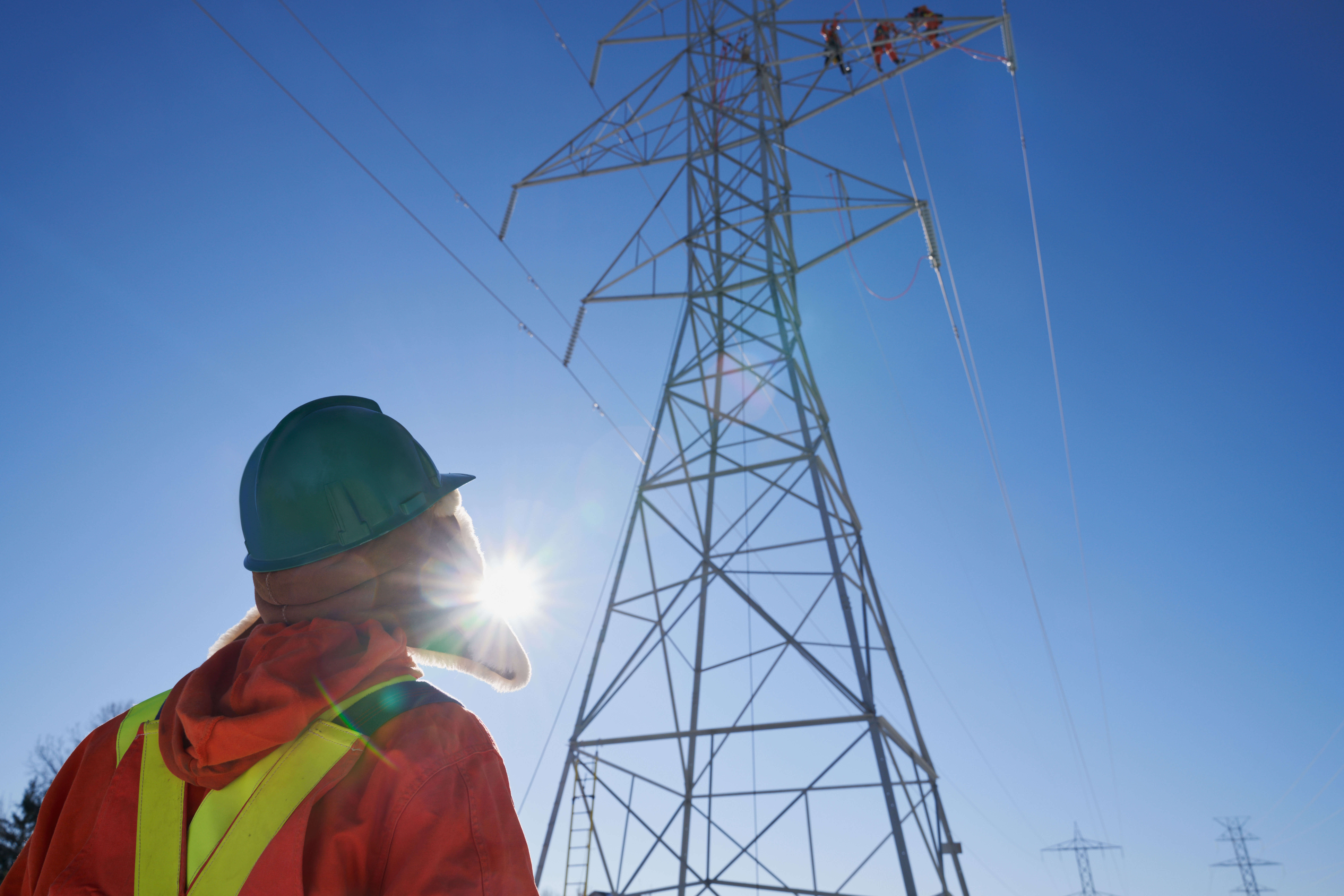 photo of a Hydro One employee standing in front of a transmission tower