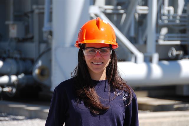 photo of a female Hydro One engineer wearing a hard hat inside a large transmission station