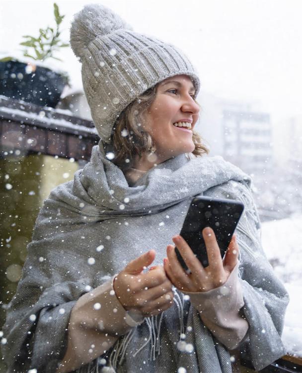 Photo of a woman using a mobile phone outside in winter