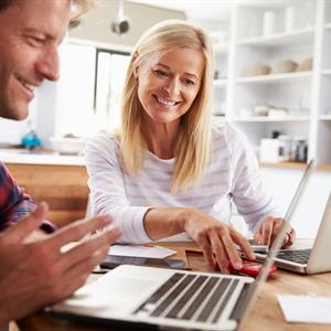 image of a man and woman doing finances using computers and a calculator