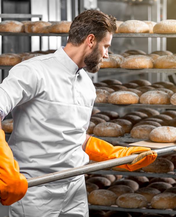 photo of a baker making bread in a large oven