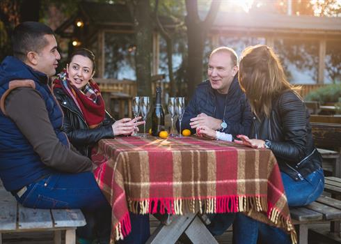 People sitting outside of a cottage talking and having wine