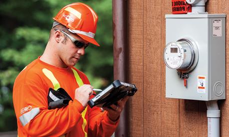 A utility worker using a handheld device near meters