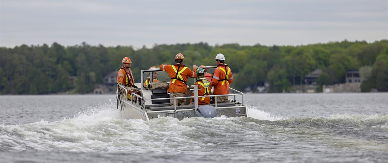 Photo of a Hydro One crew in a work boat travelling across a lake to restore power to remote locations