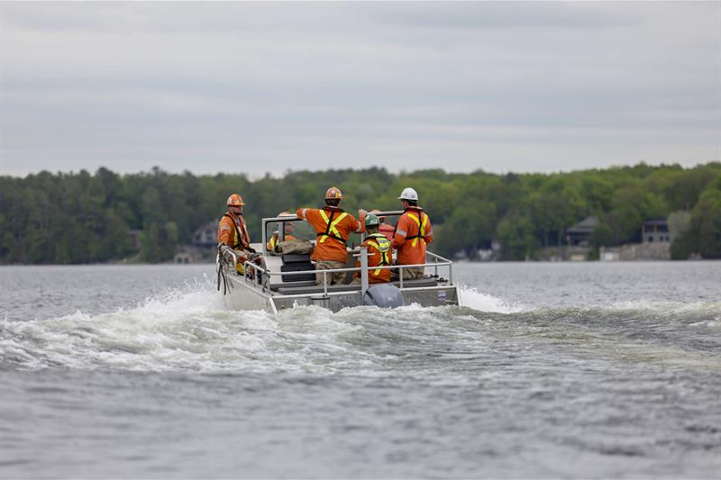 Photo of a Hydro One crew in a work boat travelling across a lake to restore power to remote locations