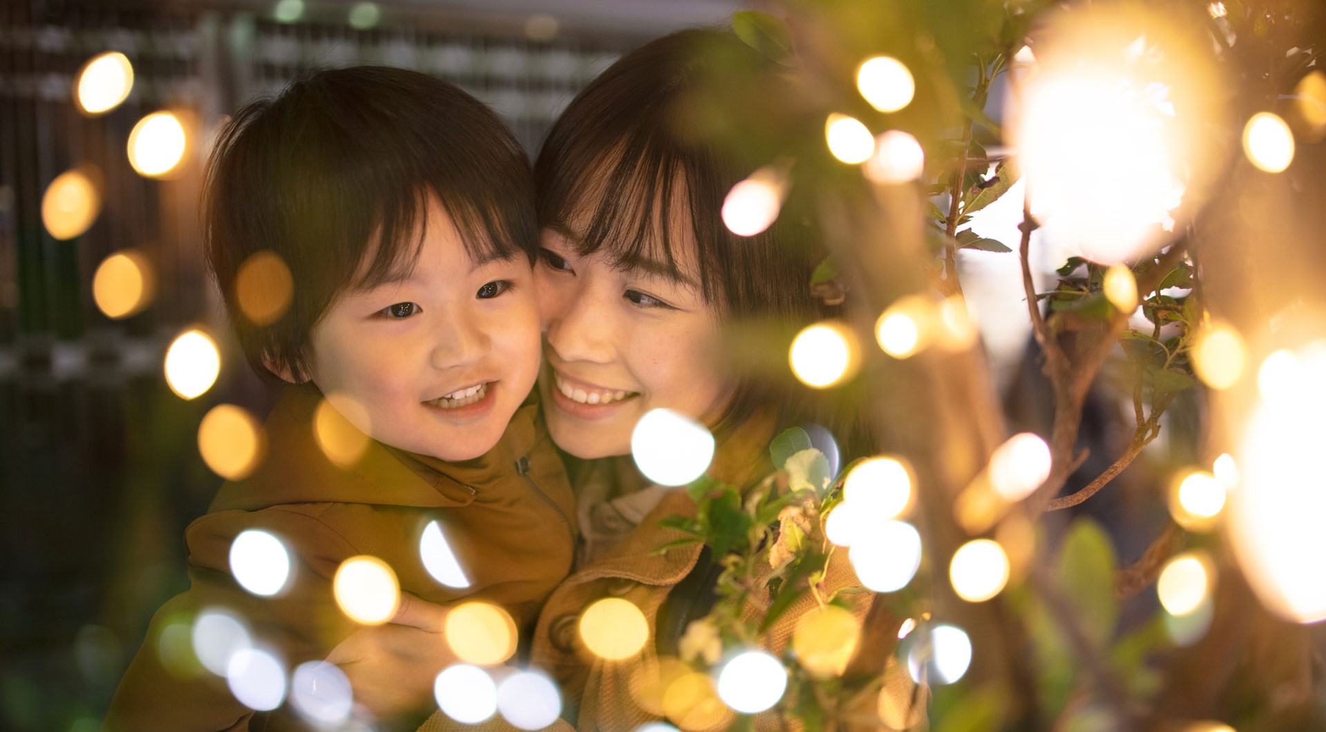 A mom and a son looking at a string of Christmas lights up close