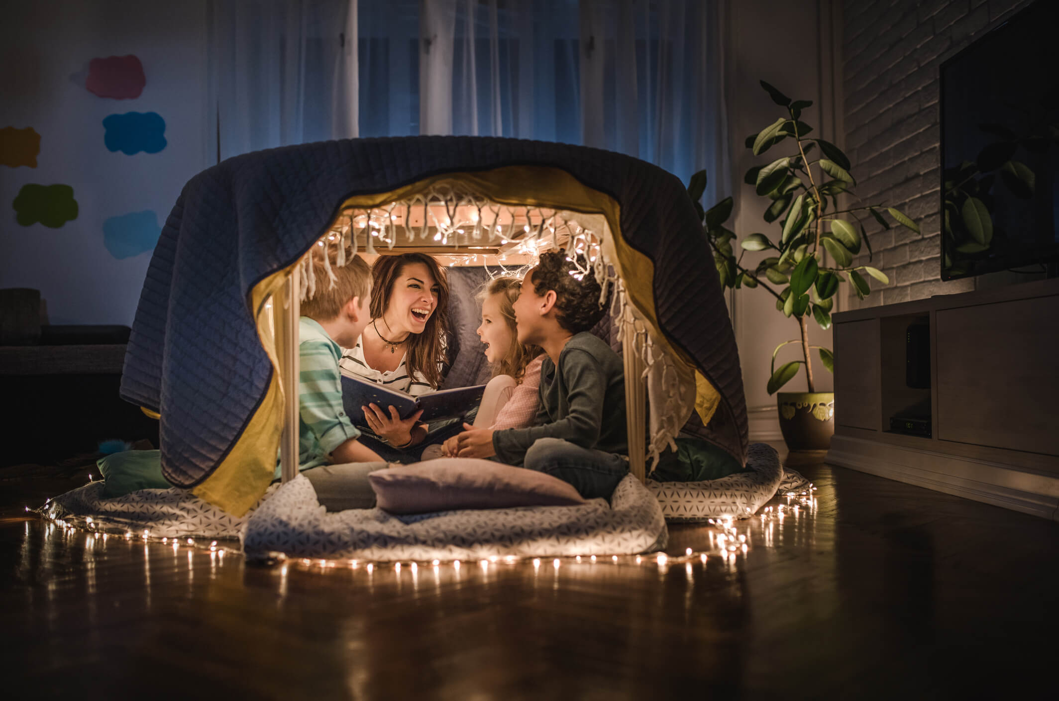 photo of a family reading in an indoor tent surrounded by electric sparkle lights
