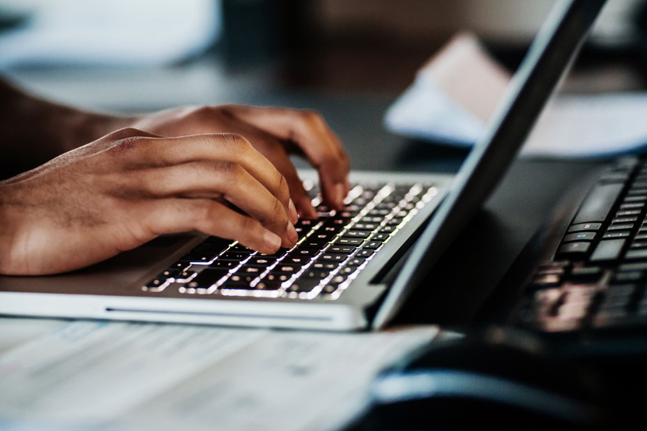 A man's hands typing on a laptop