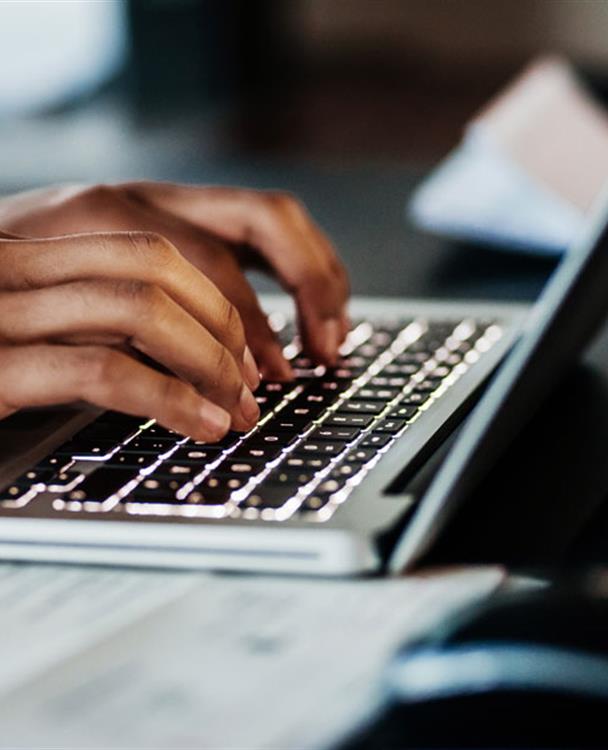 a man's hands typing on a laptop