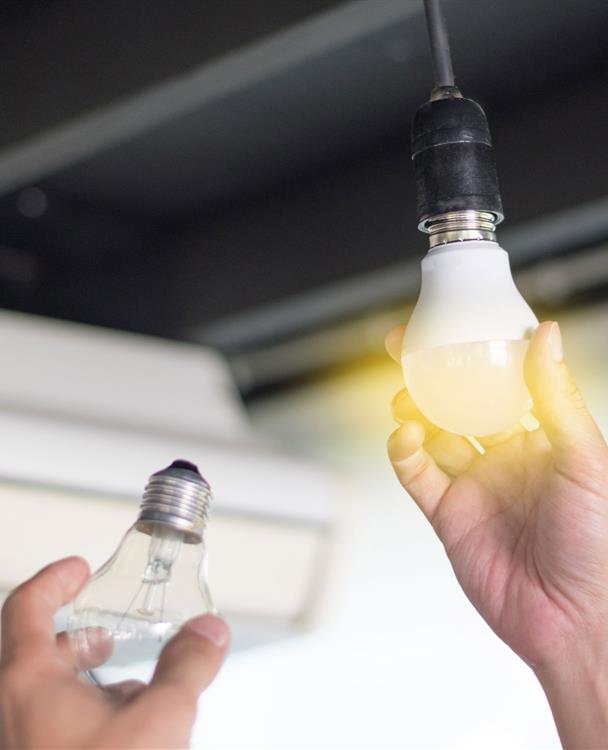 a hand screwing in an LED lightbulb