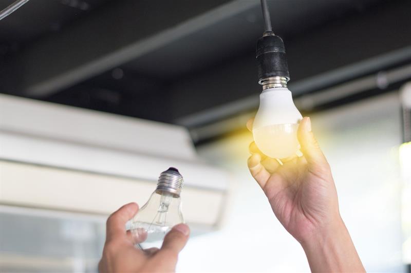 photo of a person replacing light bulbs with CFLs