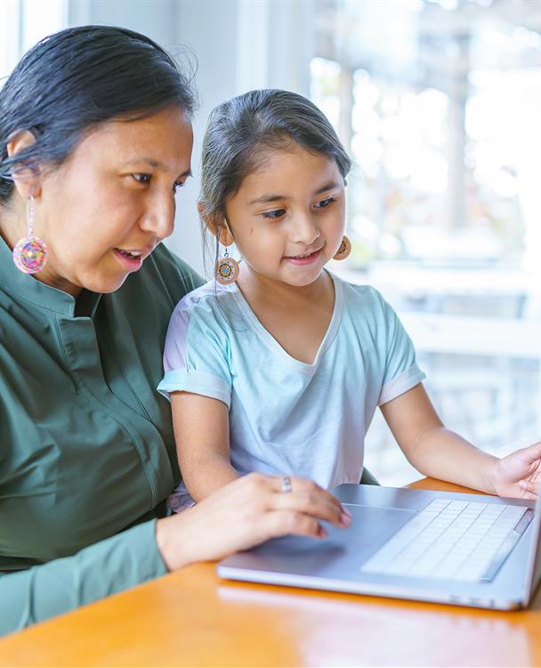 photo of an indigenous woman and her daughter using a laptop