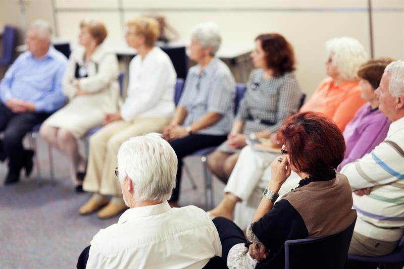 Senior citizens sitting in chairs listening to a seminar