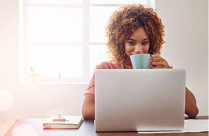 Woman drinking coffee at her laptop