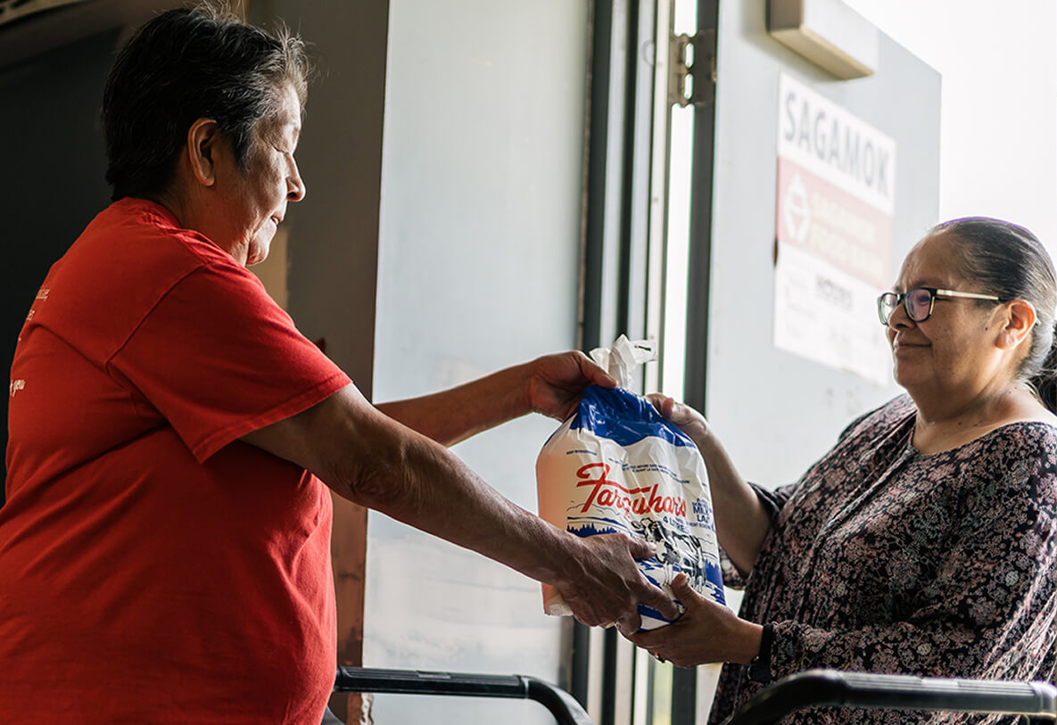 Two woman exchanging a bag of milk