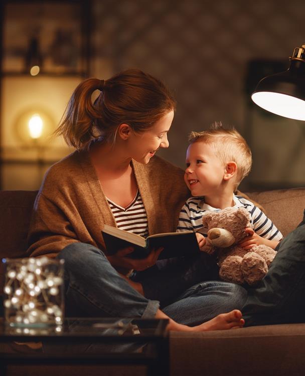 photo of a young mother reading to her toddler on a couch