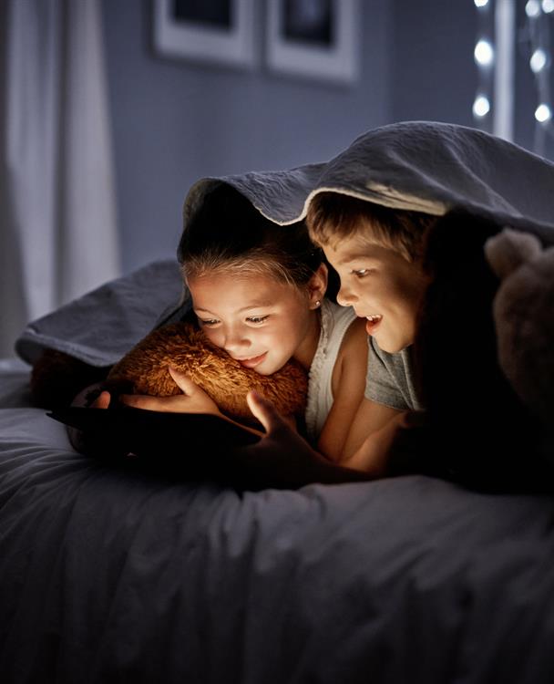 photo of two young children using an iPad under a blanket during a power outage