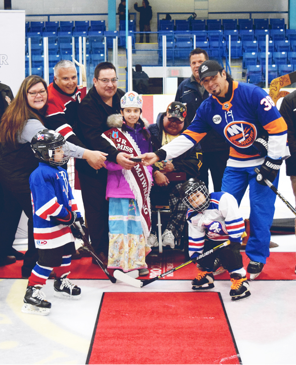 a hockey team from Little NHL huddled together for a group photo on the ice