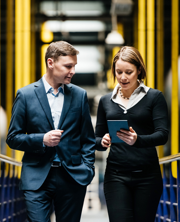 a male and a female employee walking and looking at a document