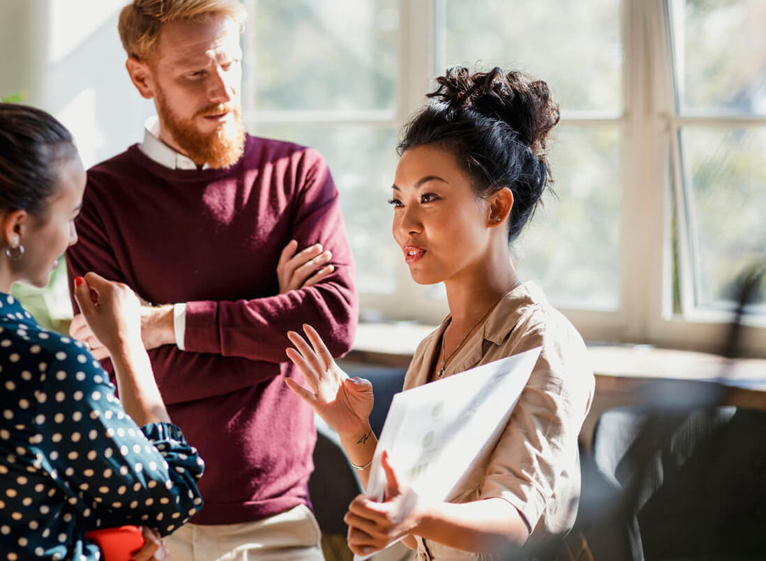 Three people conversing in an office environment