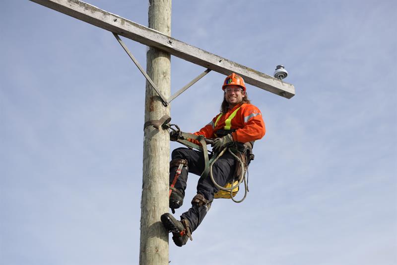photo of Eric Hutterer on the top of a distribution pole