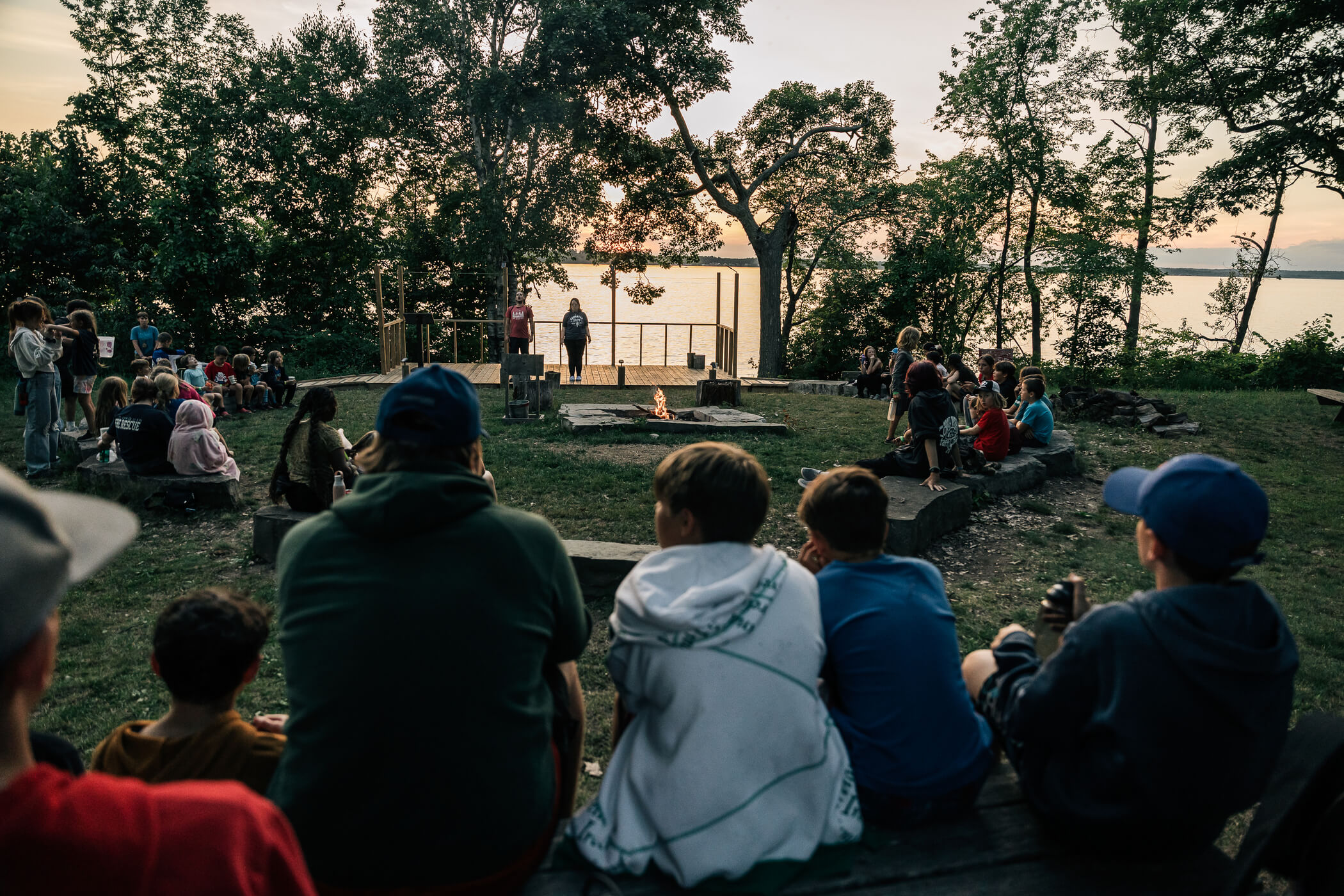 a group of people sitting on a bench watching campfire