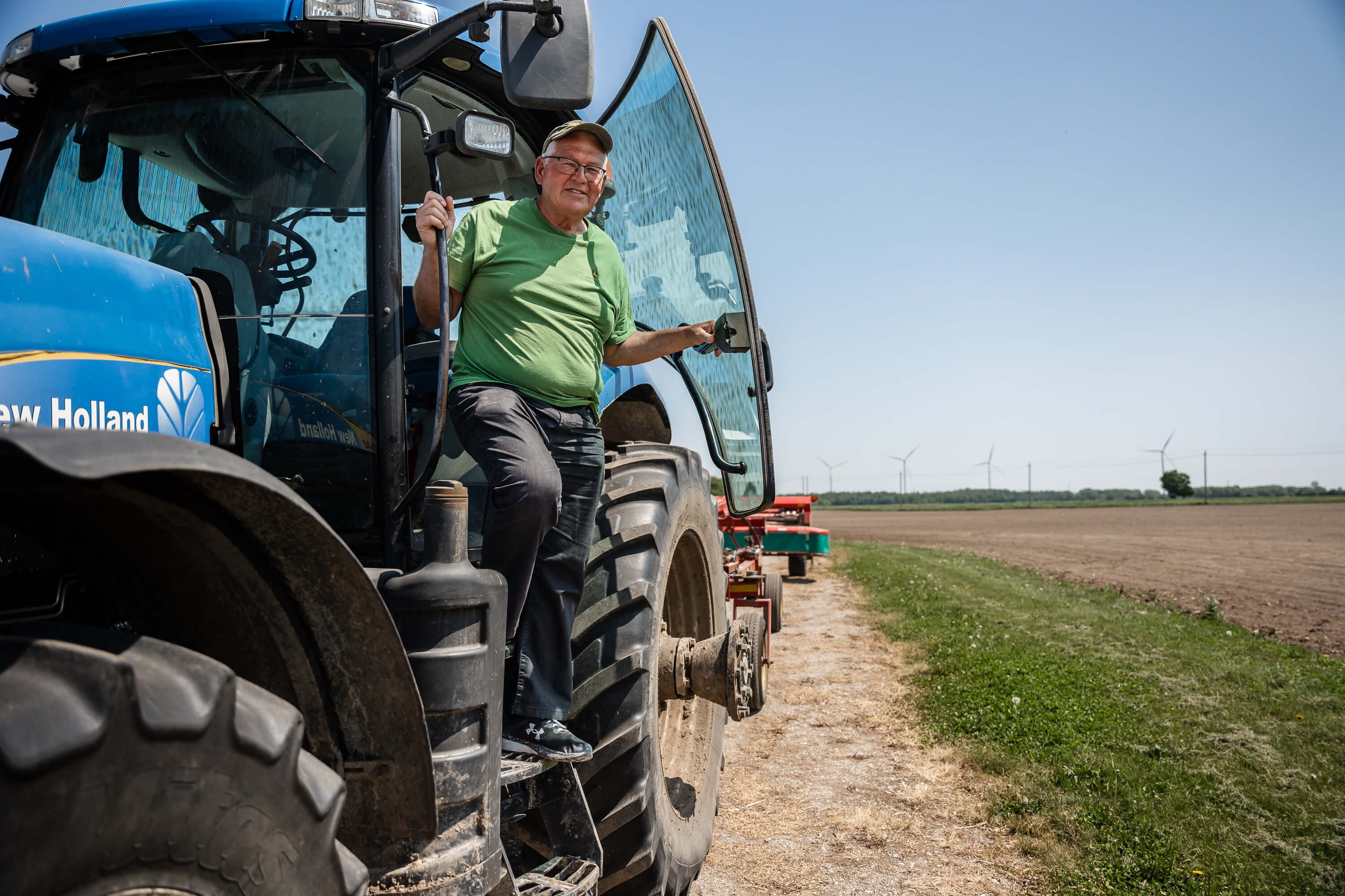 photo of Tom on his tractor beside a field