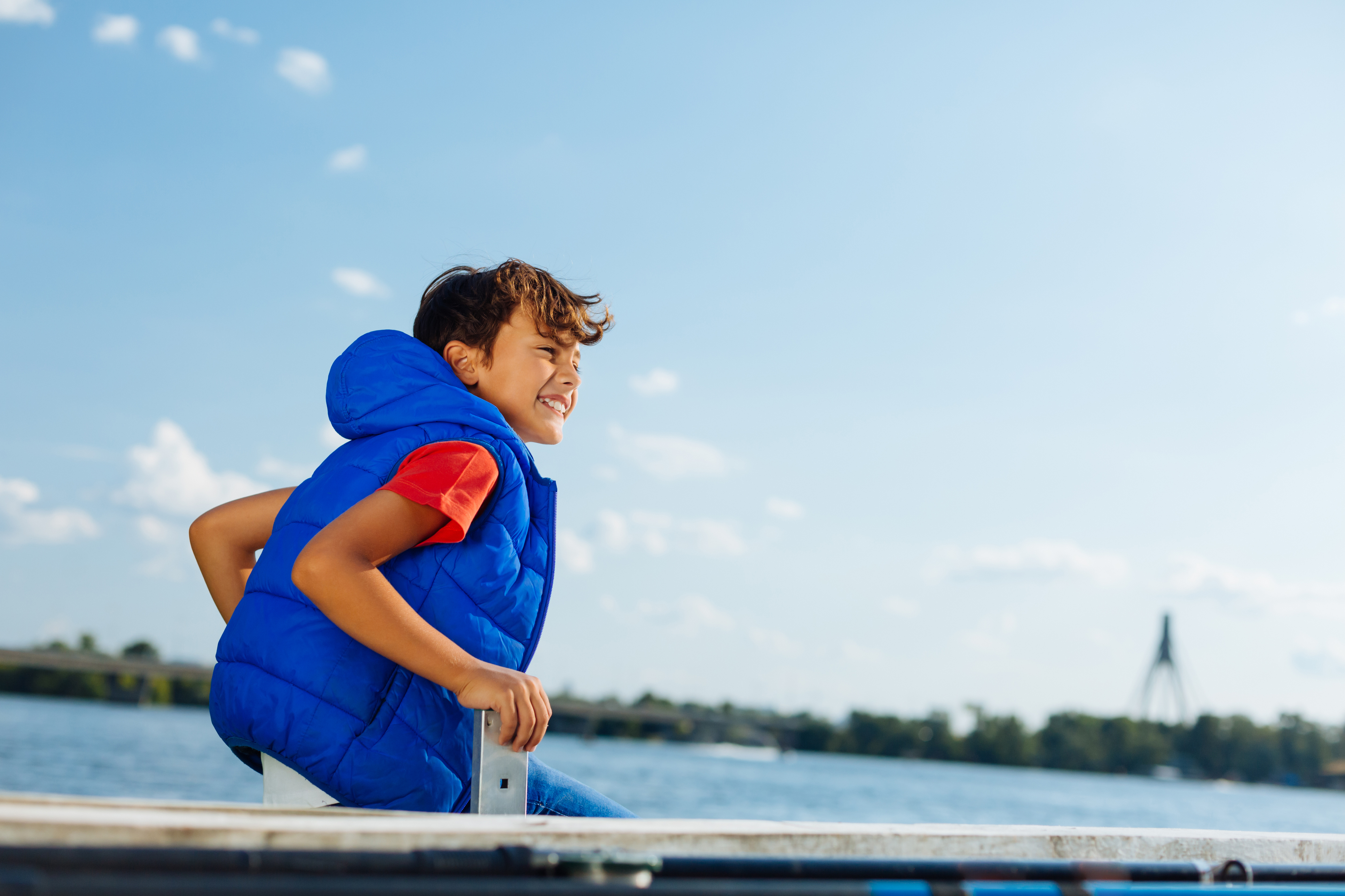 photo of a child wearing a life jacket sitting on a dock