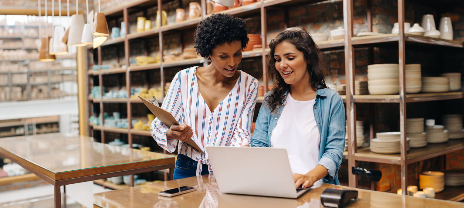 Two young shop owners using a laptop in their store