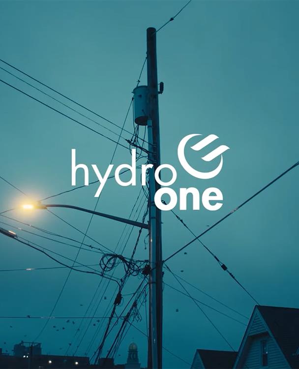 photo of Hydro One logo on a shot of a distribution pole at sunset