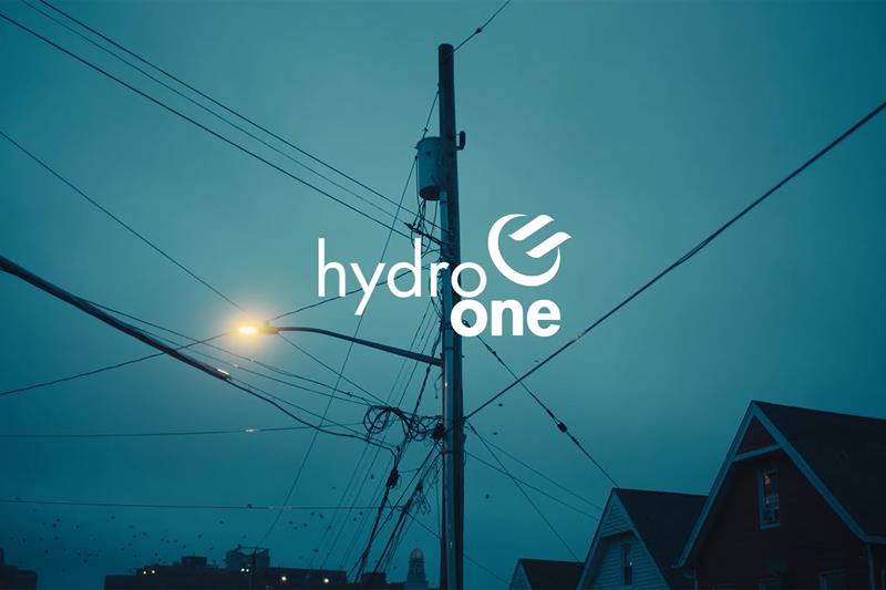photo of Hydro One logo on a shot of a distribution pole at sunset
