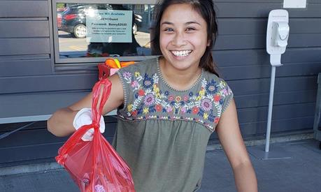 A young girl holding up a bag of food
