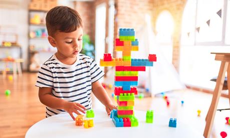 A young boy playing with blocks at a table alone