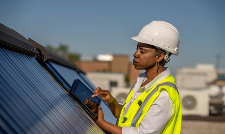 A field worker using a tablet near solar panels