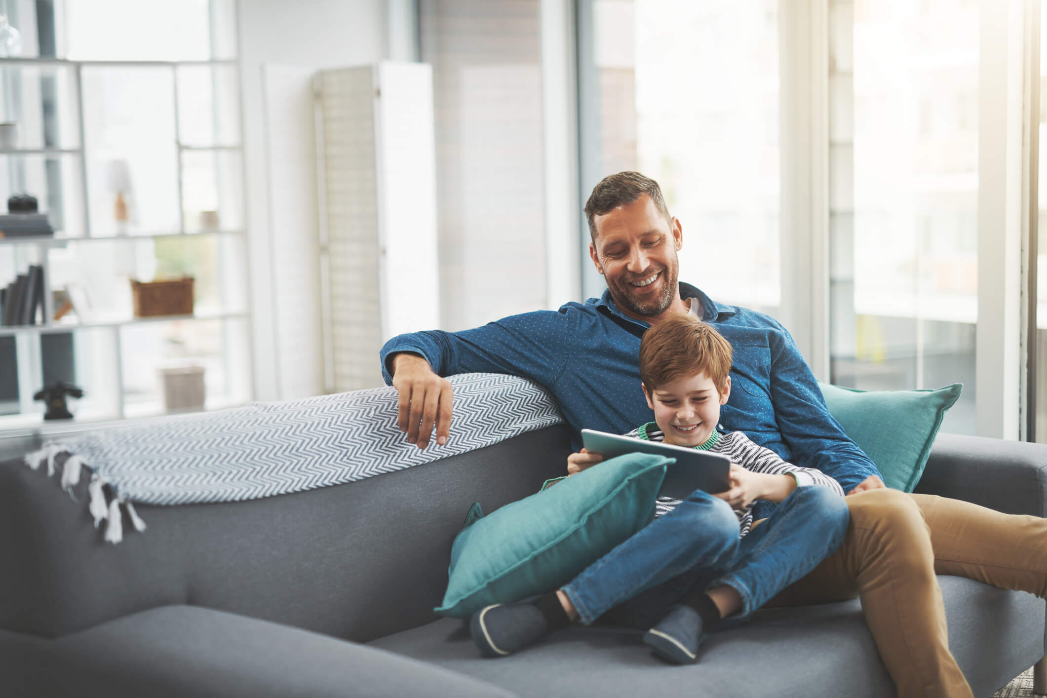 father and son looking at a tablet on the couch