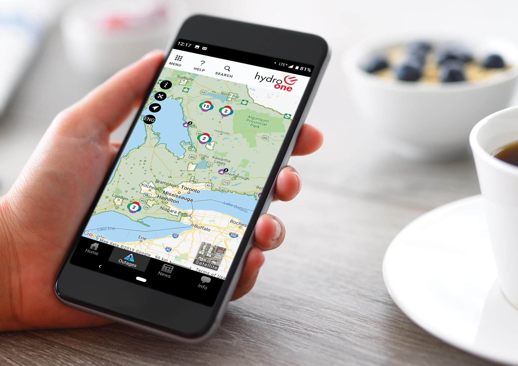 a person holding a phone - the photo is zoomed in on the phone displaying the Hydro One outage map