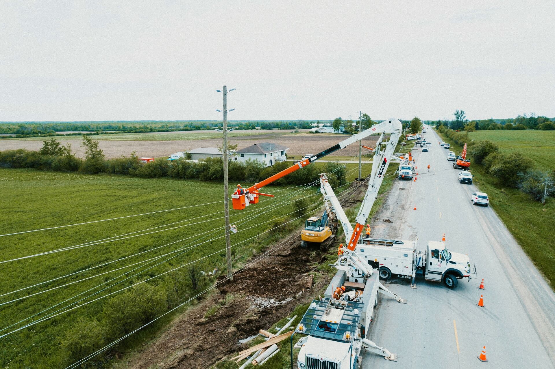 photo of several Hydro One bucket trucks doing work along a rural road